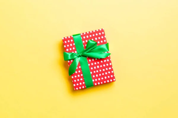 Envuelto Navidad u otro regalo hecho a mano de vacaciones en papel con cinta verde sobre fondo amarillo. Caja de regalo, decoración de regalo en mesa de colores, vista superior con espacio para copiar —  Fotos de Stock