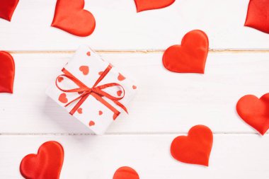 Sevgililer veya diğer tatil el yapımı mevcut kağıt ile tatil sarmalayıcı kırmızı kalpler ve hediye kutusunda. Tasarım için kopya alanı görünümüyle Beyaz ahşap masa üstü, boş alanı kutusu hediye sunmak