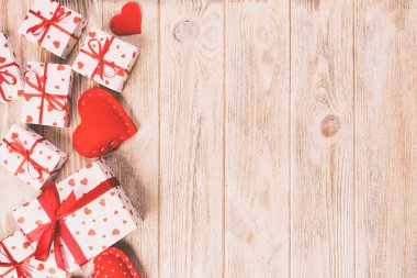 Sevgililer veya diğer tatil el yapımı mevcut kağıt ile tatil sarmalayıcı kırmızı kalpler ve hediye kutusunda. Tasarım için turuncu ahşap masa üstten görünüm kopya alanı ile boş alanı hediye kutusu
