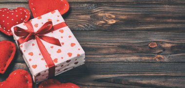 Sevgililer veya diğer tatil el yapımı mevcut kağıt ile tatil sarmalayıcı kırmızı kalpler ve hediye kutusunda. Tasarım için kopya alanı görünümüyle koyu ahşap masa üstü, boş alanı hediye kutusu