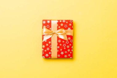 Üst manzara Noel hediyesi kutusu, sarı arka planda altın fiyonk ve kopya alanı var.
