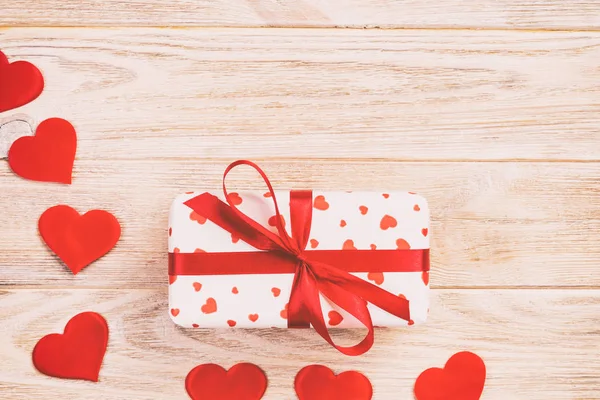 San Valentín u otro regalo hecho a mano en papel con corazones rojos y caja de regalos en envoltorio de vacaciones. Presente caja de regalo en naranja mesa de madera vista superior con espacio para copiar, espacio vacío para el diseño — Foto de Stock