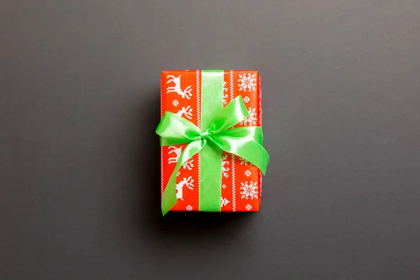 Envuelto Navidad u otro regalo hecho a mano de vacaciones en papel con cinta verde sobre fondo negro. Caja de regalo, decoración de regalo en mesa de colores, vista superior con espacio para copiar — Foto de Stock