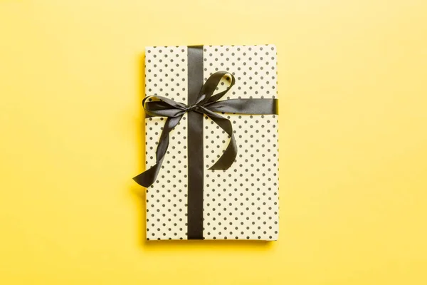 Sarı arka planda siyah kurdeleli el yapımı Noel hediyeleri. Şimdiki kutu, renkli tabloda hediye süslemesi, kopya alanı ile üst görünüm — Stok fotoğraf