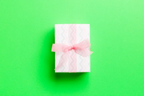 包装圣诞节或其他节日手工纸制礼物，粉红缎带绿色背景。礼品盒，彩色桌上的礼品装饰，顶部有复印空间 — 图库照片