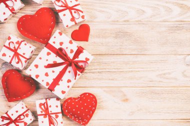 Sevgililer veya diğer tatil el yapımı mevcut kağıt ile tatil sarmalayıcı kırmızı kalpler ve hediye kutusunda. Tasarım için turuncu ahşap masa üstten görünüm kopya alanı ile boş alanı hediye kutusu