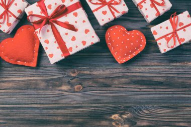 Sevgililer veya diğer tatil el yapımı mevcut kağıt ile tatil sarmalayıcı kırmızı kalpler ve hediye kutusunda. Tasarım için kopya alanı görünümüyle koyu ahşap masa üstü, boş alanı hediye kutusu