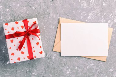 Zarf posta gri çimento arka plan üzerinde kırmızı kalp ve hediye kutulu. Sevgililer günü kartı, aşk veya kavramı tebrik düğün