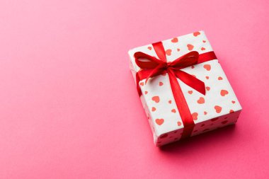Hediye kutusu ile kırmızı kurdele ve kalp üzerinde pembe bir arka plan, metin kopyalama yeri olan üstten görünüm
