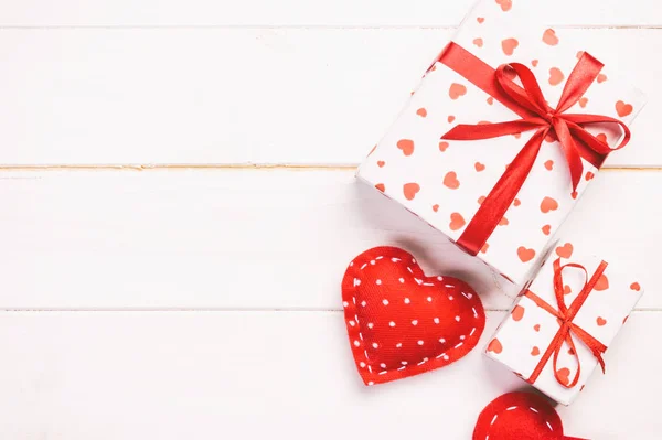 San Valentín u otro regalo hecho a mano en papel con corazones rojos y caja de regalos en envoltorio de vacaciones. Regalo de caja de regalo en vista superior de mesa de madera blanca con espacio de copia, espacio vacío para el diseño — Foto de Stock