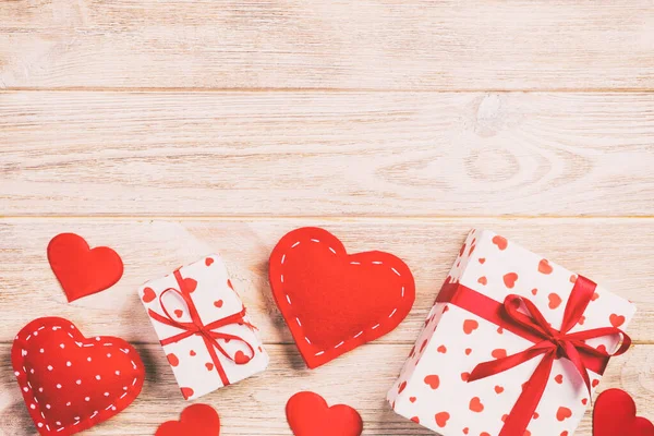 San Valentín u otro regalo hecho a mano en papel con corazones rojos y caja de regalos en envoltorio de vacaciones. Presente caja de regalo en naranja mesa de madera vista superior con espacio para copiar, espacio vacío para el diseño — Foto de Stock