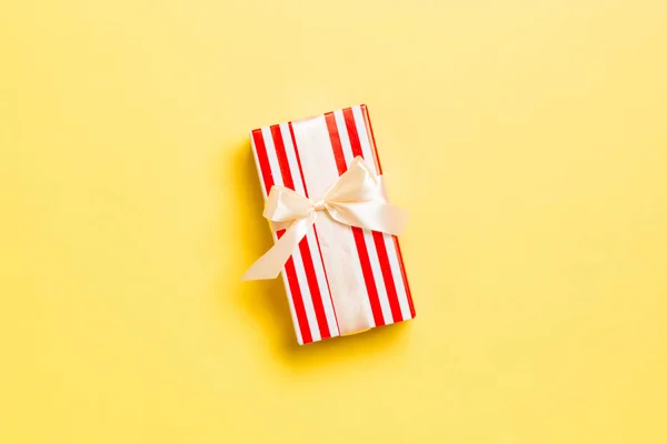 Sarı arkaplanlı sarı kurdeleli el yapımı Noel hediyeleri. Şimdiki kutu, renkli tabloda hediye süslemesi, kopya alanı ile üst görünüm — Stok fotoğraf