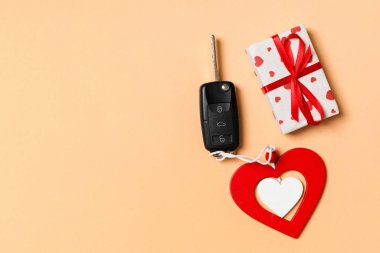 Hediye kutusunun üst görüntüsü, araba anahtarı ve renkli arka planda tahta kalp. Sevgililer Günü için lüks hediye