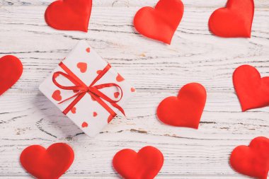 Sevgililer veya diğer tatil el yapımı mevcut kağıt ile tatil sarmalayıcı kırmızı kalpler ve hediye kutusunda. Tasarım için kopya alanı görünümüyle Beyaz ahşap masa üstü, boş alanı hediye kutusu