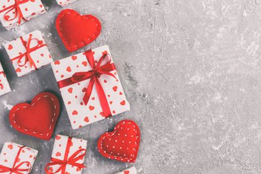 Sevgililer veya diğer tatil el yapımı mevcut kağıt ile tatil sarmalayıcı kırmızı kalpler ve hediye kutusunda. Kopya alanı, tasarım için boş alan ile gri çimento tablo üstten görünüm hediye kutusu mevcut