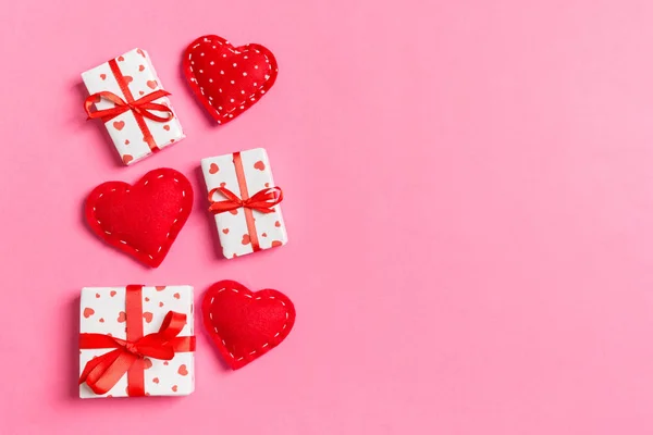 Holiday composition of gift boxes and red textile hearts on colorful background with empty space for your design. Top view of Valentine\'s Day concept