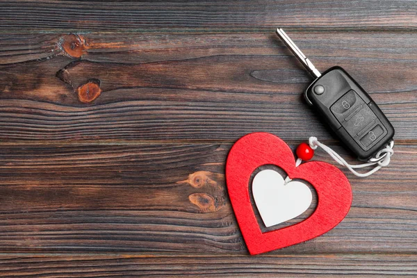 Top view of car key and heart as a present for Valentine's day on wooden background. Romance concept with copy space