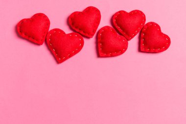 Renkli arka planda tekstil kırmızısı kalplerin kompozisyonu ve tasarımın için boş alan. Sevgililer Günü konseptinin en üst görüntüsü