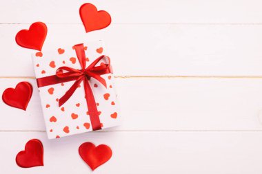 Sevgililer veya diğer tatil el yapımı mevcut kağıt ile tatil sarmalayıcı kırmızı kalpler ve hediye kutusunda. Tasarım için kopya alanı görünümüyle Beyaz ahşap masa üstü, boş alanı kutusu hediye sunmak