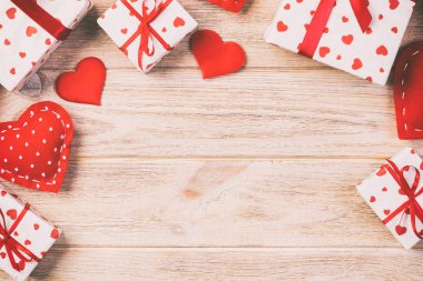 Sevgililer veya diğer tatil el yapımı mevcut kağıt ile tatil sarmalayıcı kırmızı kalpler ve hediye kutusunda. Tasarım için turuncu ahşap masa üstten görünüm kopya alanı ile boş alanı hediye kutusu