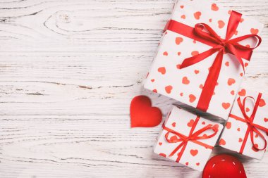 Sevgililer veya diğer tatil el yapımı mevcut kağıt ile tatil sarmalayıcı kırmızı kalpler ve hediye kutusunda. Tasarım için kopya alanı görünümüyle Beyaz ahşap masa üstü, boş alanı hediye kutusu