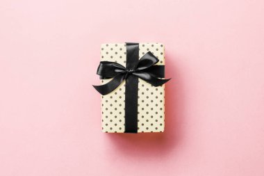 Noel için siyah fiyonklu hediye kutusu ya da pembe arka planda yeni yıl günü, fotokopi alanı olan üst görünüm
