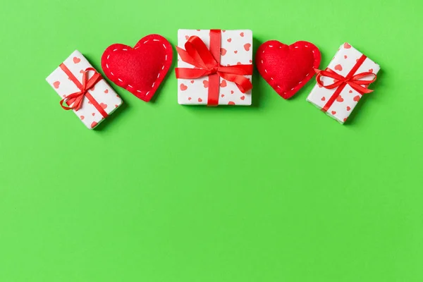 Holiday composition of gift boxes and red textile hearts on colorful background with empty space for your design. Top view of Valentine\'s Day concept