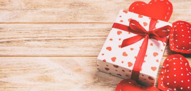 Sevgililer veya diğer tatil el yapımı mevcut kağıt ile tatil sarmalayıcı kırmızı kalpler ve hediye kutusunda. Tasarım için turuncu ahşap masa üstten görünüm kopya alanı ile boş alanı hediye kutusu