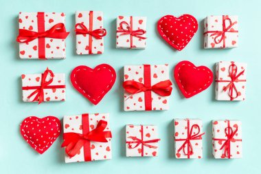 Beyaz hediye kutularının ve renkli arka planda kırmızı tekstil kalplerinin kompozisyonu. Sevgililer Günü konsepti