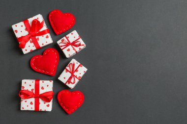 Hediye kutularının ve renkli arka planda kırmızı tekstil kalplerinin üst görüntüsü. Kopya alanı ile Sevgililer Günü konsepti