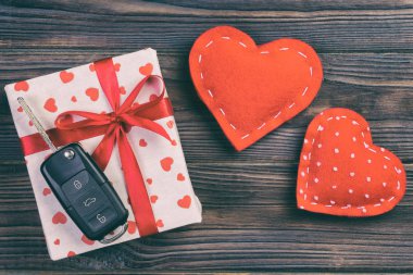 Sevgililer günü ya da diğer tatil hediyeleri kırmızı kalpler, araba anahtarları ve tatil ambalajında hediye paketi. Koyu ahşap masa üstü görünümlü kutu hediyesi kopyalama alanı, tasarım için boş alan