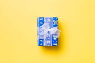 Sarı arka planda beyaz kurdeleli el yapımı Noel hediyeleri. Şimdiki kutu, renkli tabloda hediye süslemesi, kopya alanı ile üst görünüm
