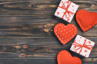 Sevgililer veya diğer tatil el yapımı mevcut kağıt ile tatil sarmalayıcı kırmızı kalpler ve hediye kutusunda. Tasarım için kopya alanı görünümüyle koyu ahşap masa üstü, boş alanı hediye kutusu