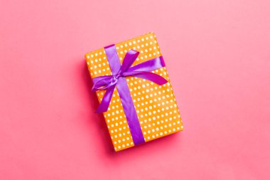 Yaşayan mercan arka planında mor kurdeleli el yapımı Noel hediyeleri. Şimdiki kutu, renkli tabloda hediye süslemesi, kopya alanı ile üst görünüm