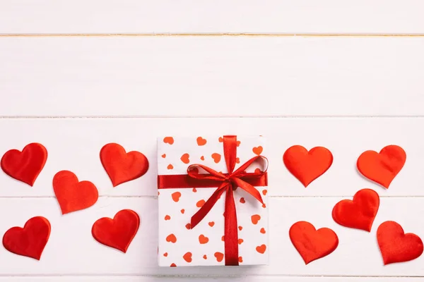 Valentin vagy más holiday kézzel jelen van papír, piros szívek és ajándék doboz a holiday wrapper. Jelen doboz ajándék a fehér fa asztallap Kilátás-val másol hely, üres hely tervezés — Stock Fotó