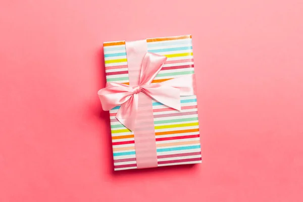 用粉红缎带包裹在活珊瑚背景上的圣诞礼物或其他手工制作的节日礼物。 礼物盒，彩色桌子上的礼物装饰，顶部有复印空间 — 图库照片