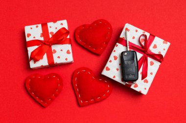 Hediye kutusundaki araba anahtarının üst görüntüsü ve renkli arka plandaki kırmızı tekstil kalpleri. Sevgililer Günü konsepti için hediye