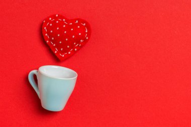 Kırmızı tekstil kalplerinin renkli arka planda bir bardaktan fışkırması. Sevgililer günün kutlu olsun.