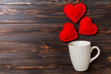 Bardağın üst görüntüsü ve kırmızı kalpler ahşap arka planda düşüyorlar. Sevgililer günün kutlu olsun.