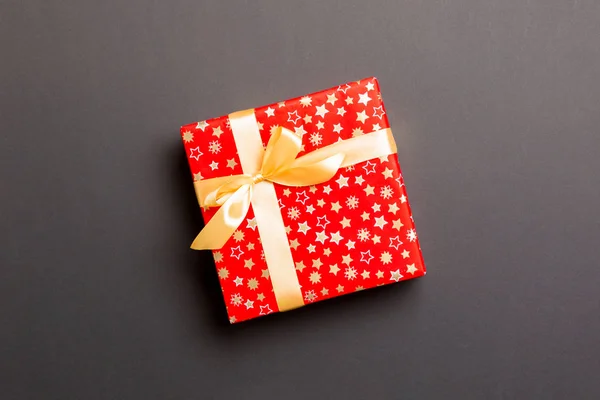 Τυλιγμένο Χριστούγεννα ή άλλες γιορτές χειροποίητο δώρο σε χαρτί με χρυσή κορδέλα σε μαύρο φόντο. Παρουσιάστε το κιβώτιο, διακόσμηση του δώρου στο χρωματιστό τραπέζι, top view με το διάστημα αντιγράφων — Φωτογραφία Αρχείου