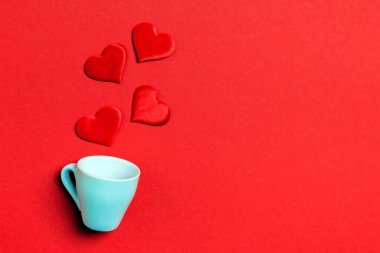 Kırmızı kalplerin üst görünüm kompozisyonu fotokopi alanı ile renkli arkaplandaki bir bardaktan dökülüyor. Romantik ilişki kavramı. Aziz Valentaine Günü