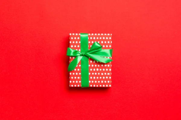 Üst görünüm Noel hediyesi kutusu, kırmızı arkaplanda yeşil fiyonk ve kopyalama alanı — Stok fotoğraf