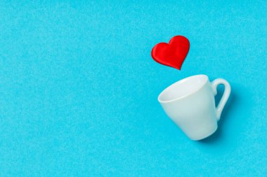 Kırmızı kalplerin renkli arka planda bir bardaktan düşüşünün bayram kompozisyonu. Kopya alanı ile Sevgililer Günü konseptinin en üst görüntüsü