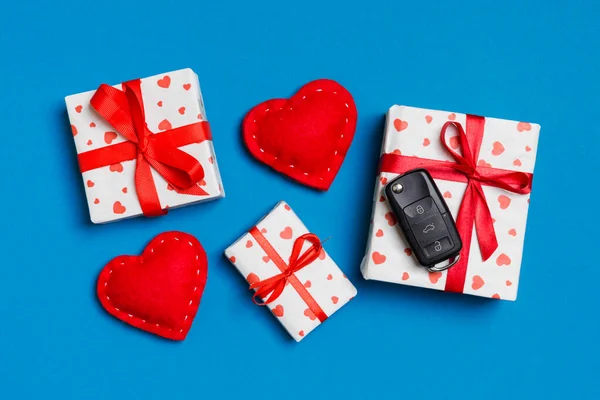Ovanifrån av bil nyckel på presentförpackning och röda textila hjärtan på färgglada bakgrund. Present för alla hjärtans dag koncept — Stockfoto