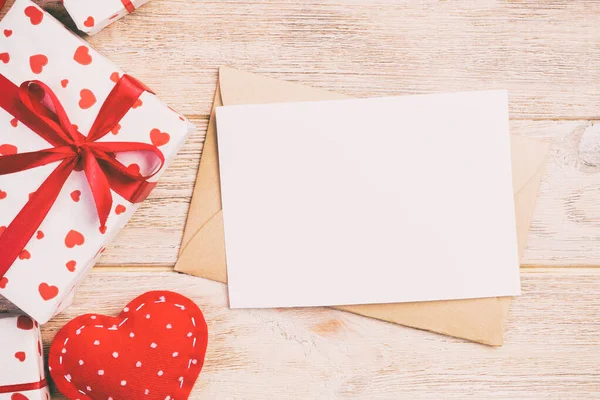 Envolvente de correo con corazón rojo y caja de regalo sobre fondo de madera naranja. Tarjeta de San Valentín, Amor o Boda Concepto de Saludo — Foto de Stock