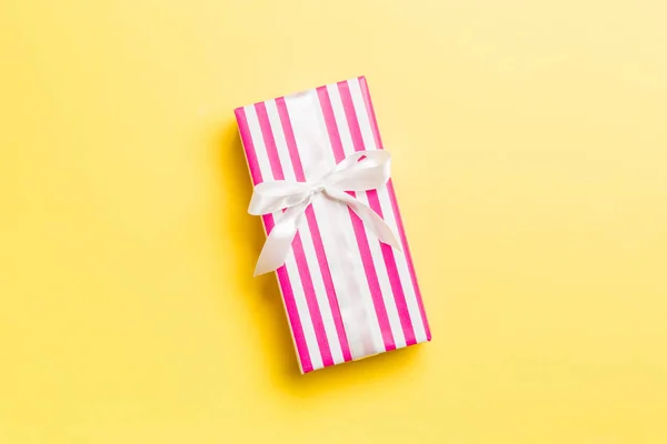 Üst görünüm Noel hediyesi kutusu, üzerinde beyaz fiyonk ve kopya alanı olan sarı arkaplan — Stok fotoğraf