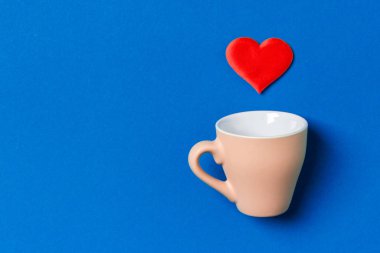 Kırmızı kalplerin renkli arka planda bir bardaktan düşüşünün bayram kompozisyonu. Kopya alanı ile Sevgililer Günü konseptinin en üst görüntüsü