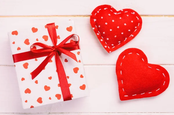 San Valentín u otro regalo hecho a mano en papel con corazones rojos y caja de regalos en envoltorio de vacaciones. Regalo de caja de regalo en vista superior de mesa de madera blanca con espacio de copia, espacio vacío para el diseño — Foto de Stock
