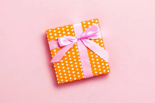 Enveloppé Noël ou autre cadeau de vacances fait à la main en papier avec ruban rose sur fond rose. Coffret cadeau, décoration de cadeau sur table colorée, vue de dessus avec espace de copie — Photo