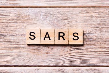 Ahşap blokta Sars kelimesi yazıyor. Koronavirüs konseptin için ahşap masanın üzerinde Sars metni.